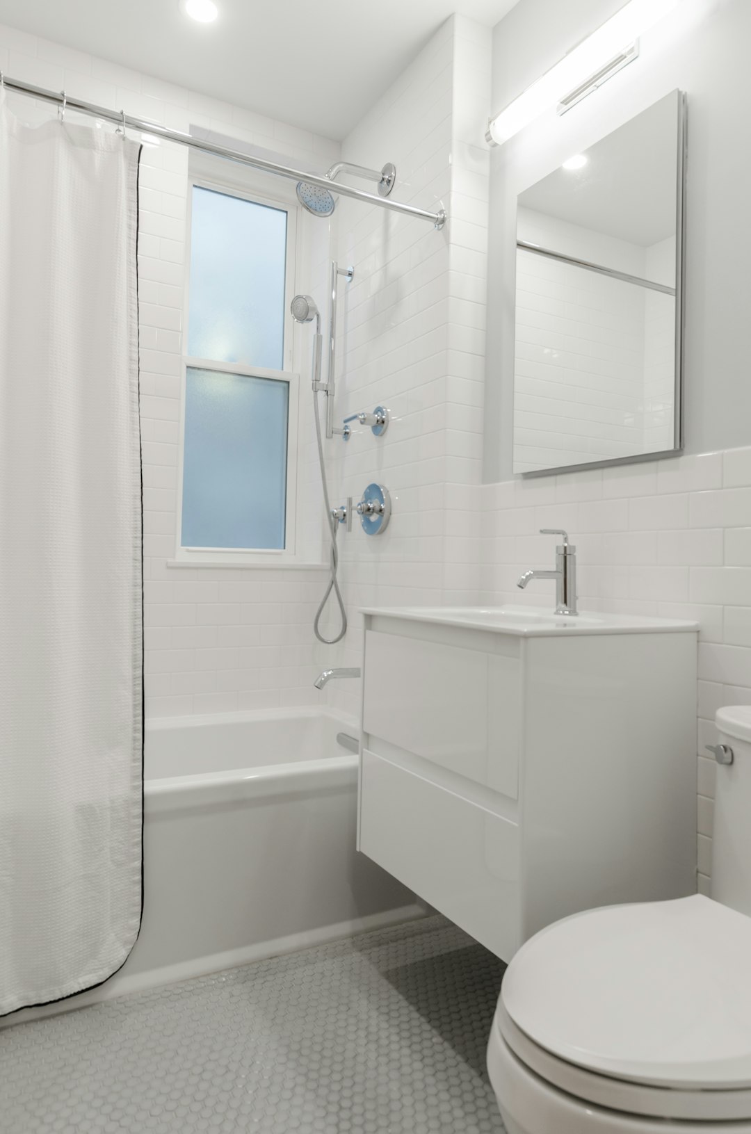 All white bathroom, white bathroom tiles, white subway  tiles, chrome faucets, chrome shower head, chrome finishings, bathroom mirror, crystal door knob
